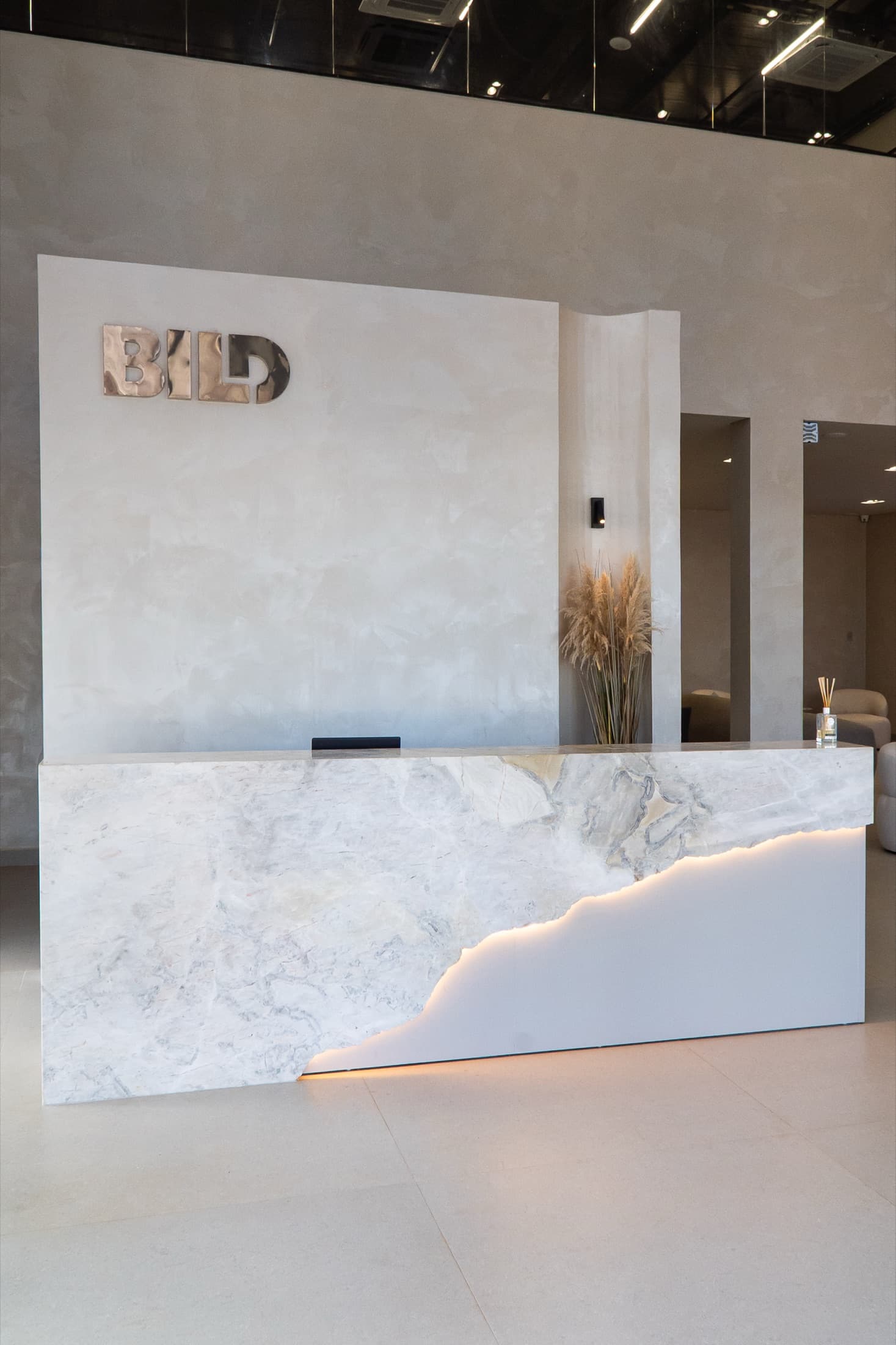 Recepção em mármore com marcenaria sob medida e iluminação embutida - projeto Bild House